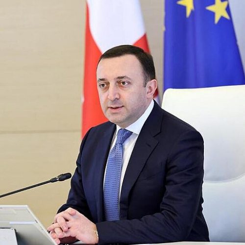 Irakli Garibasvili, at a government conference in 2023, and a European flag in the background.