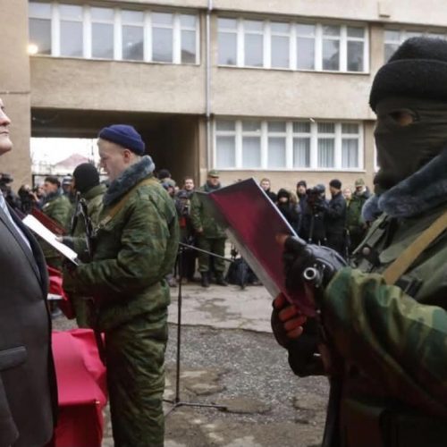 Simferopol, Krim, 10. mars 2014. Sergej Aksjonov, den prorussiske statsministeren på Krim, står foran et maskert og bevæpnet medlem av en prorussisk selvforsvarsstyrke som avlegger troskapsed til de nye myndighetene. Seremonien fant sted mens Russland var i ferd med å konsolidere sin militære og politiske kontroll over den ukrainske halvøya, seks dager før den omstridte folkeavstemningen.
Fotograf: Vasily Fedosenko / Reuters. Reuters' bildearkiv bekrefter både datoen, stedet og fotografens navn.
